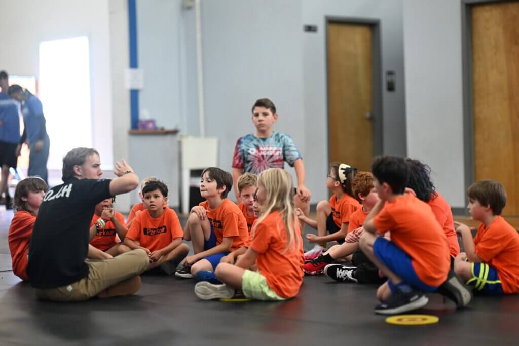 Children sitting on the floor listening to their coach