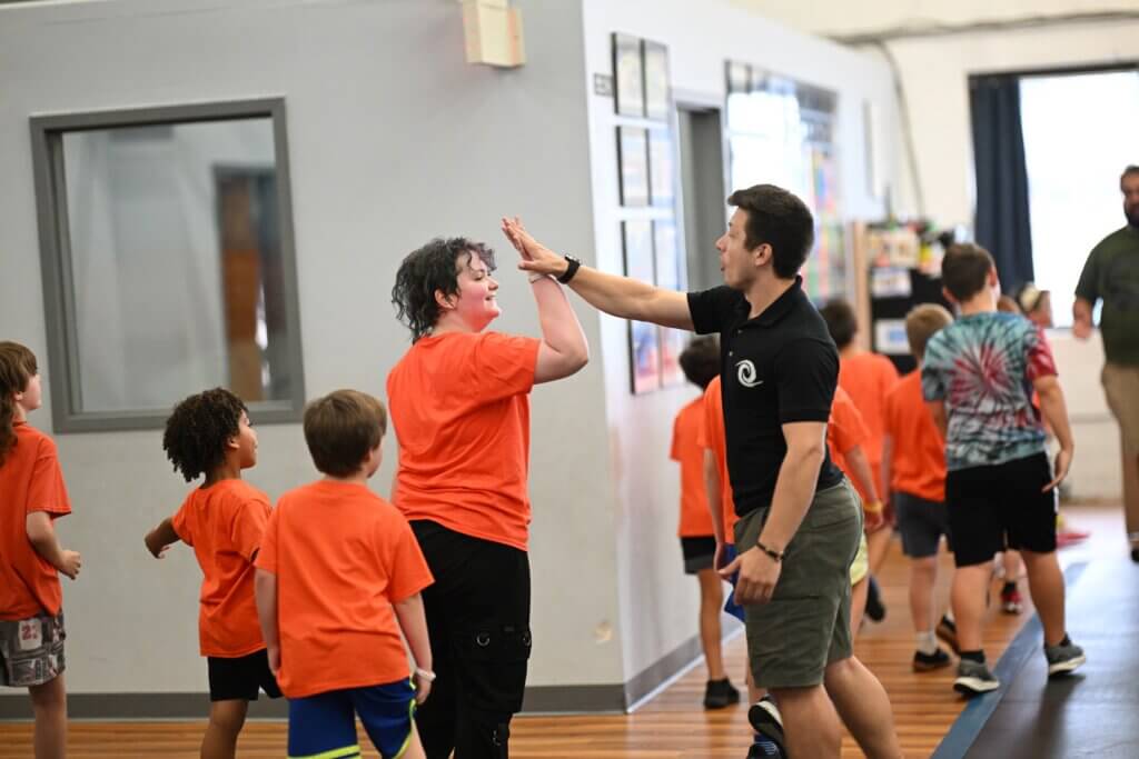 Coach high-fiving a child during a parkour class