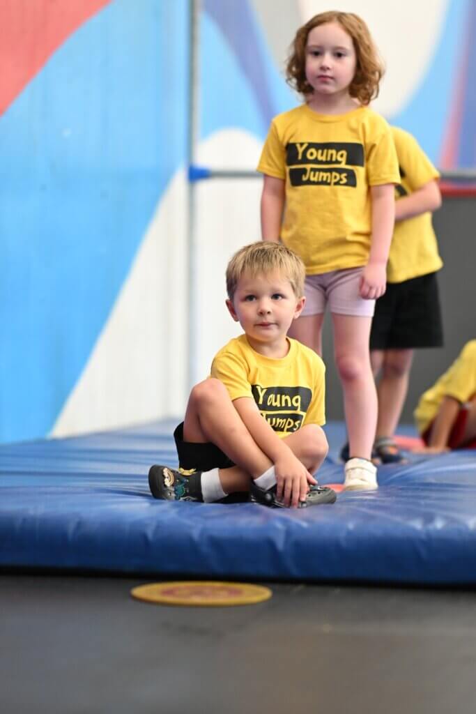 Young Jumps - kids on mat Two preschoolers in Young Jumps shirts sitting together on a gym mat