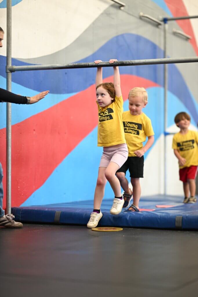 Young Jumps - hanging from bar Young girl hanging from a low bar during a Young Jumps parkour class