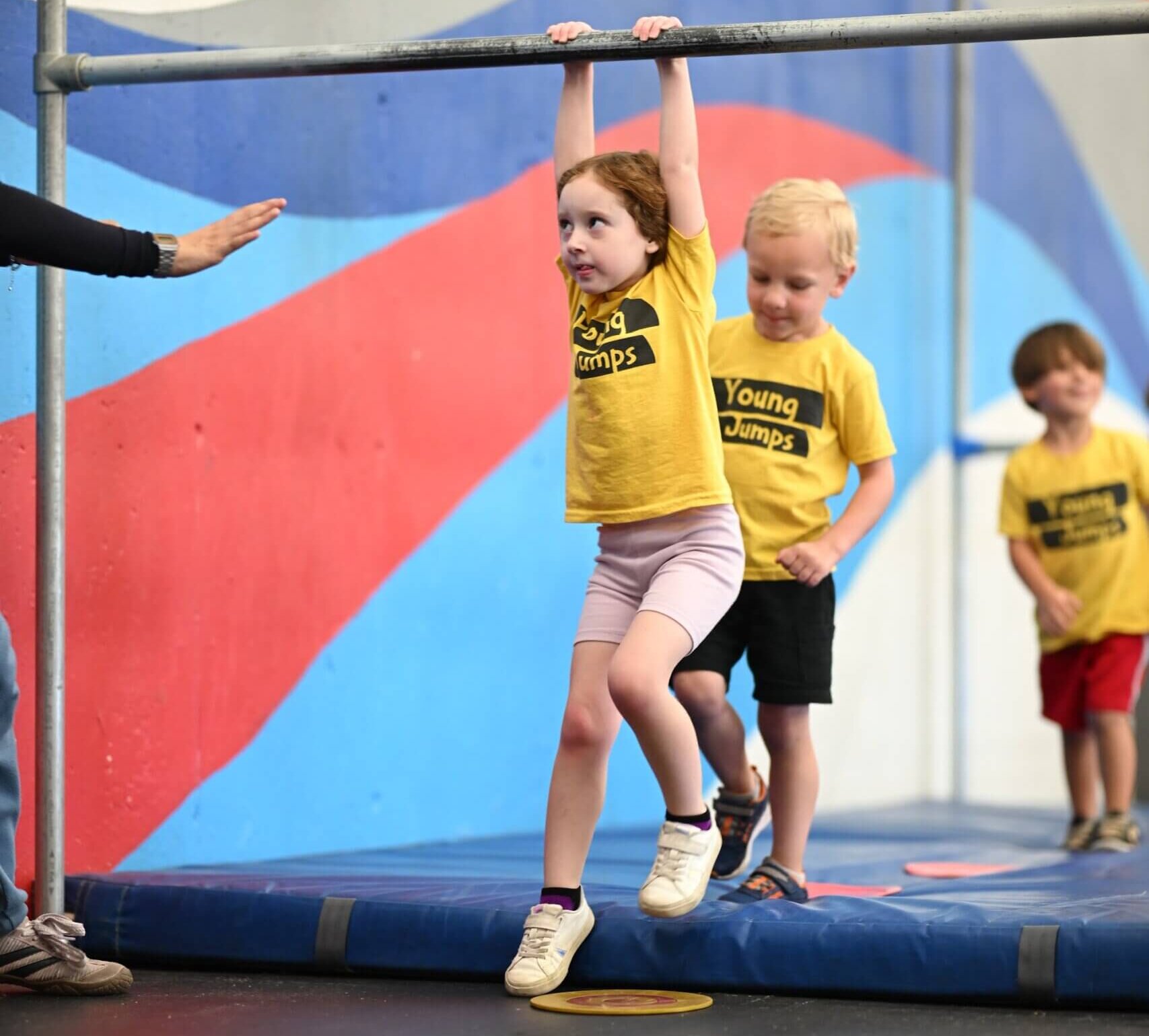 Young Jumps - hanging from bar Young girl hanging from a low bar during a Young Jumps parkour class
